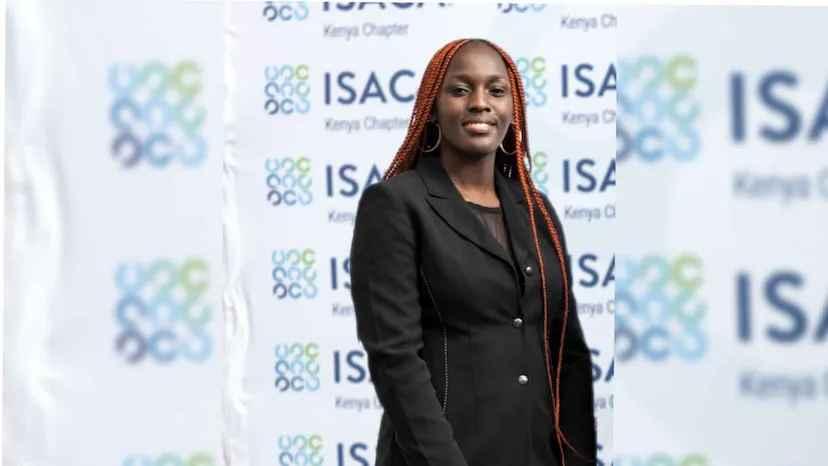 Susan Khasoa, the founder of Project Digital, smiles, standing in a black Blazer with long red braided hair and hoop earrings. In the background is an ISAC Kenya Chapter backdrop.