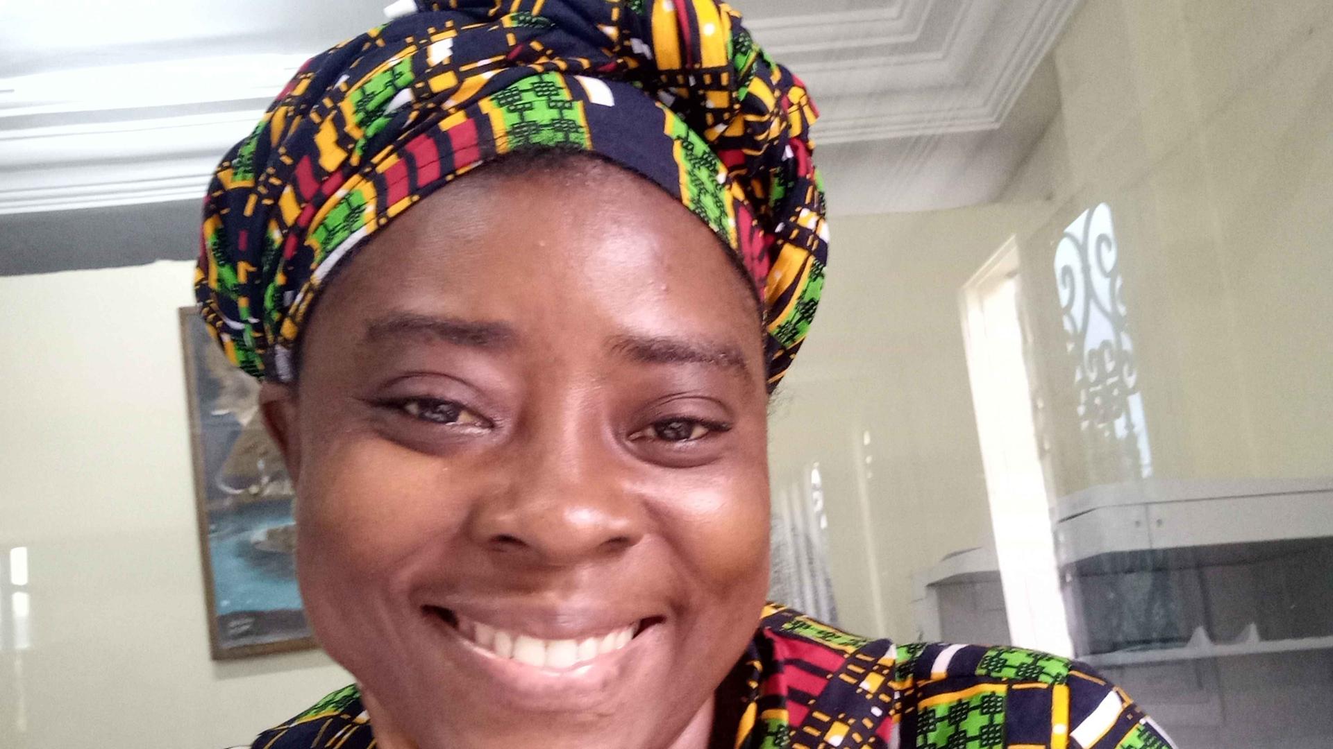 I am wearing a colourful, green Ankara (African Fabric) with a headscarf and a bright smile.